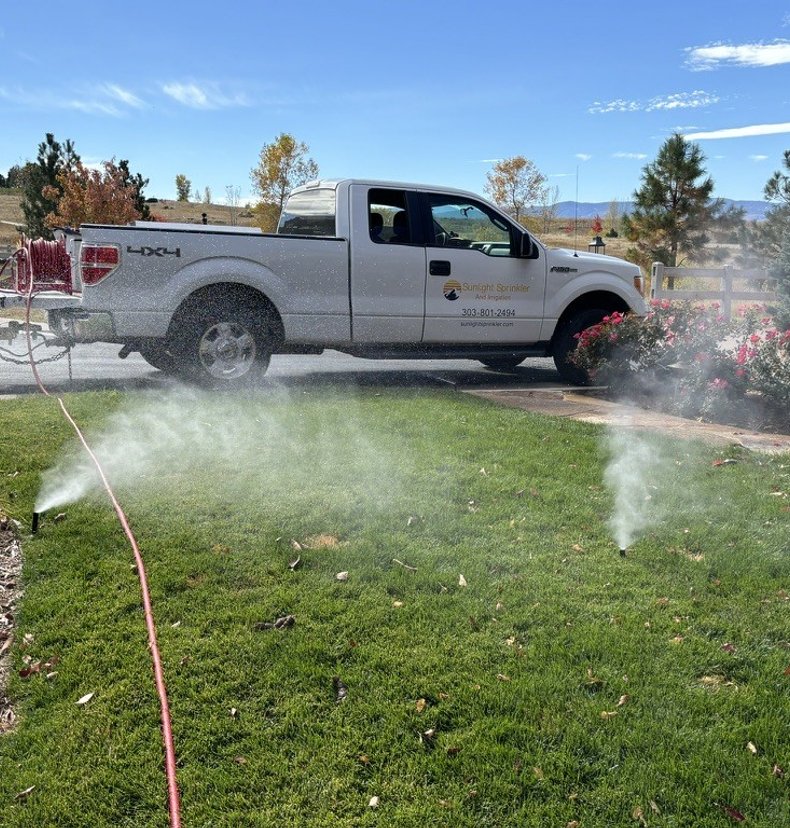Sprinkler heads misting during a fall winterization blowout at a Denver metro home