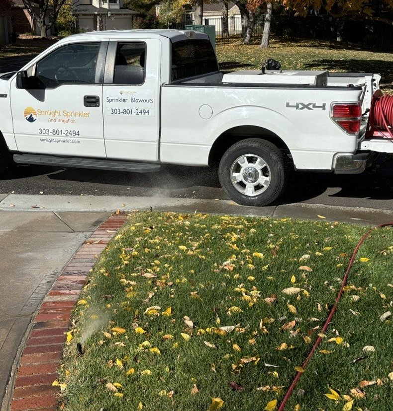 Sunlight Sprinkler blowout service truck with hose reel at a Denver metro residence in fall