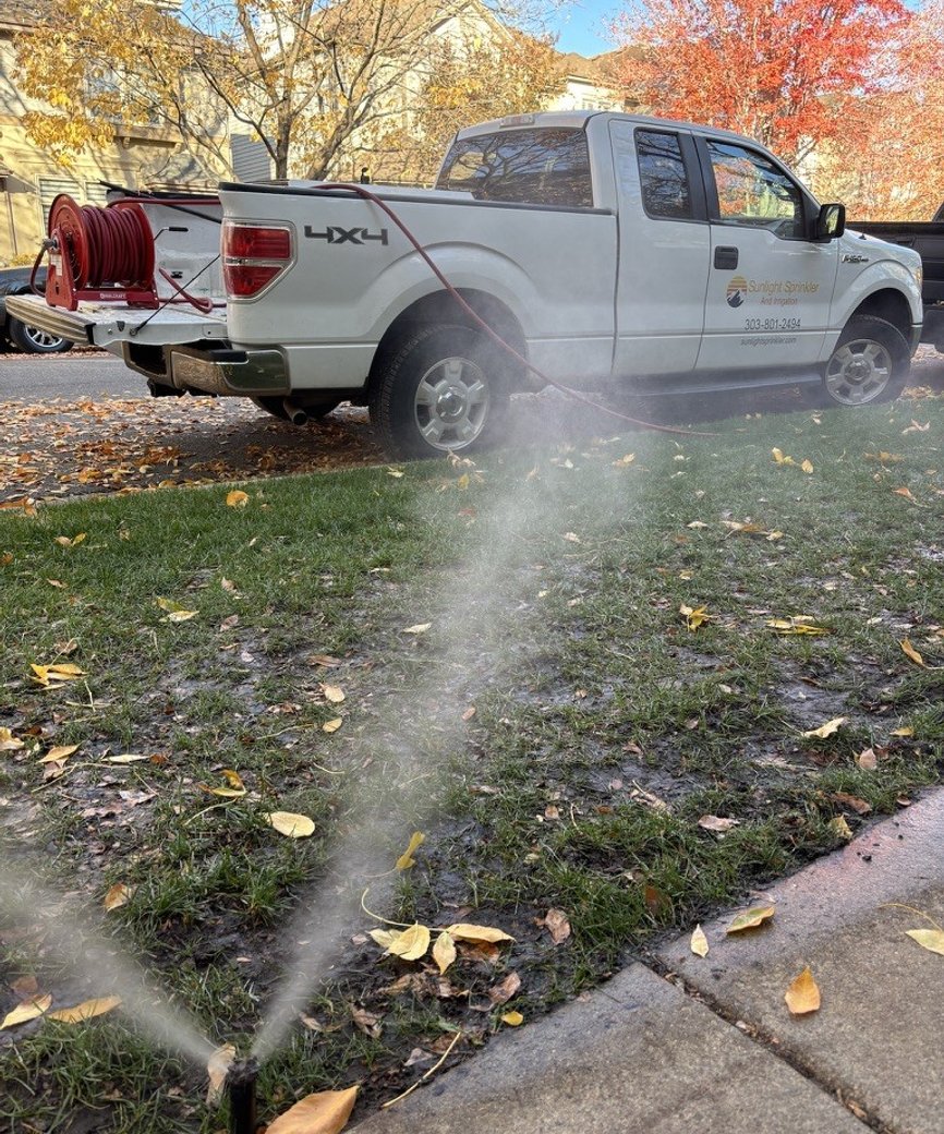 Sunlight Sprinkler truck and compressor performing a fall sprinkler blowout on a leaf covered lawn